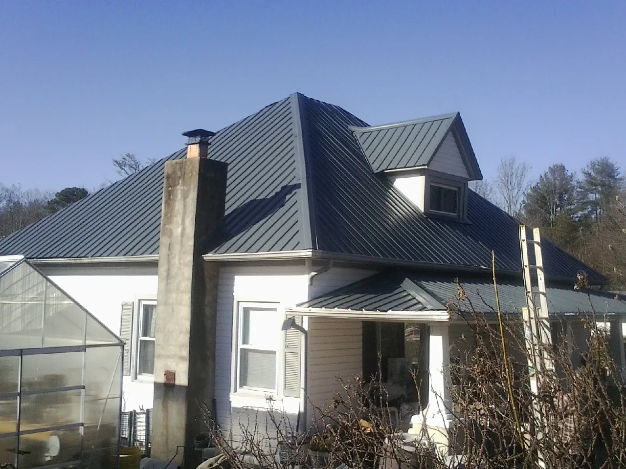 Dark blue standing seam metal roof on a white farmhouse with dormer — Slate & Tile Roof Repair by Roofing Brothers in Blain