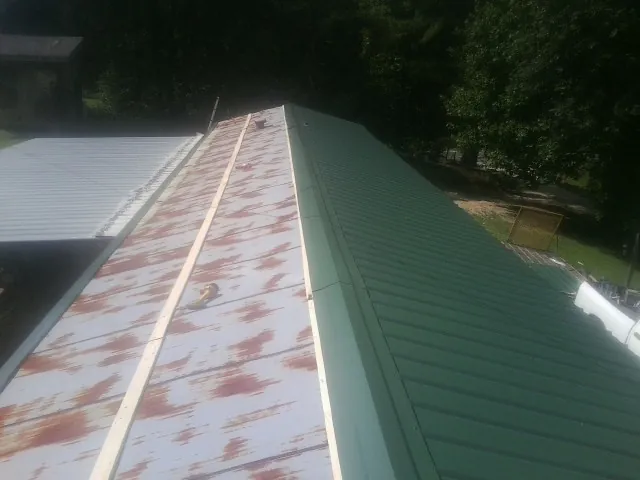 Old rusted panels beside newly installed green metal roofing — Wind Damage Roof Repair by Roofing Brothers in Blain