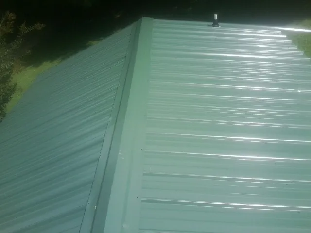 New green metal panels meeting at the ridge of a roof — Flat Roof Repair work by our crew in Blain