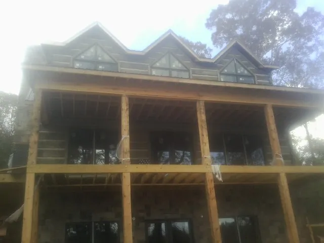 Dormers and porch framing on a large log home under construction — Roof Coating work by our crew in Blain