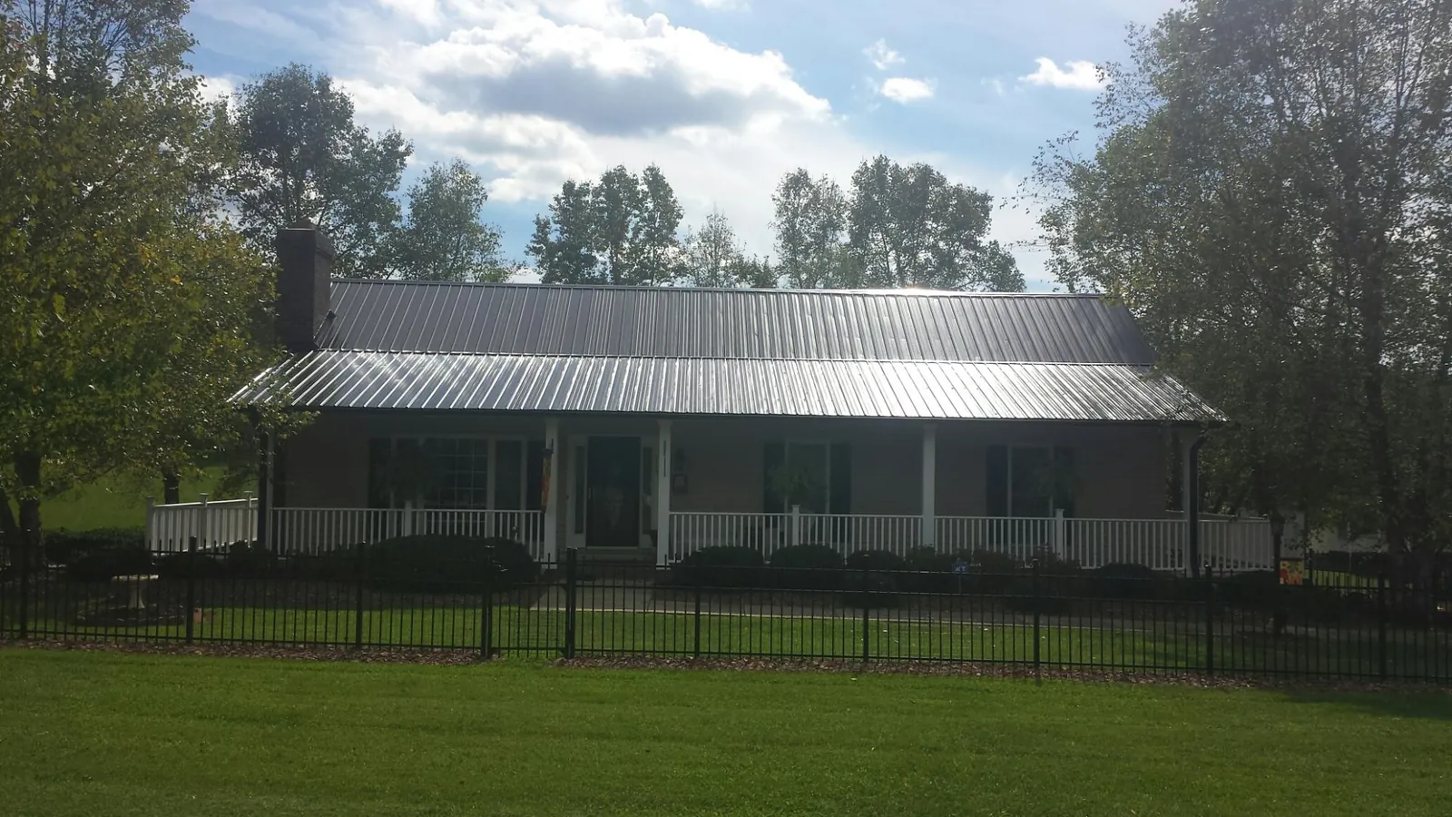 Gray metal roof on a brick ranch with a full width front porch — Gutter Guard Installation work by our crew in Blain