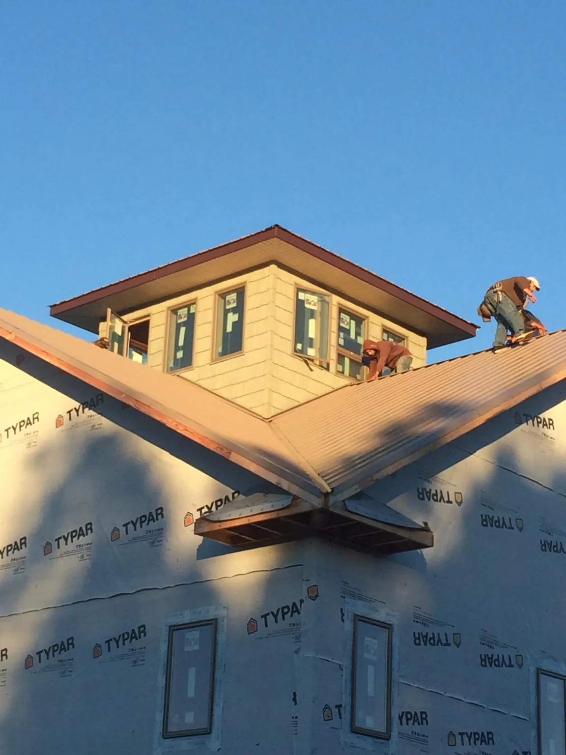 Roofers working around a rooftop cupola on a new metal roof at sunset — Roof Waterproofing in Blain by Roofing Brothers